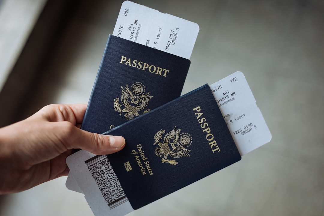 A hand holding two United States passports with airline boarding passes tucked inside